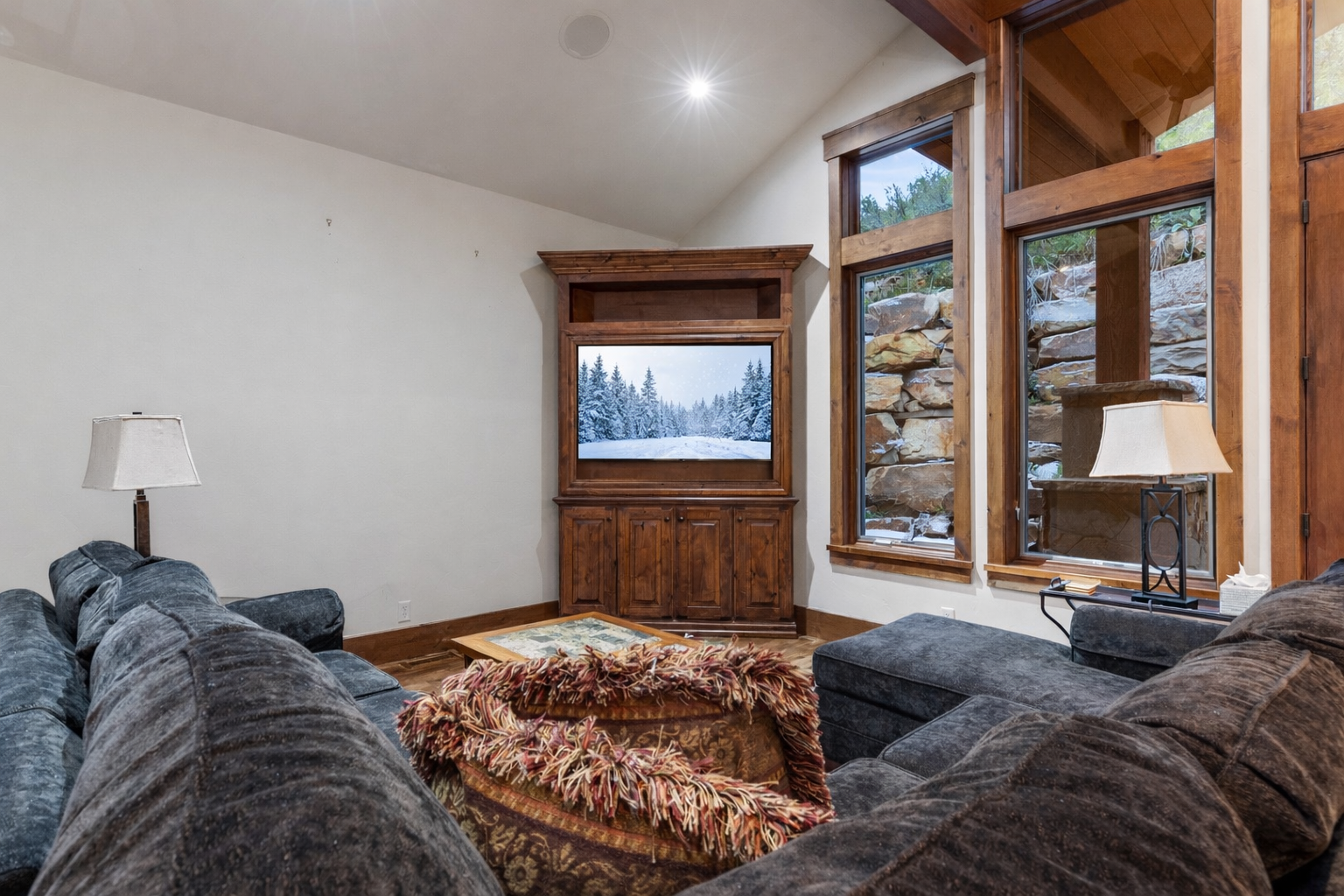 Relax in our cozy living room featuring a large sectional sofa, big-screen TV, and stunning mountain views through the expansive windows.