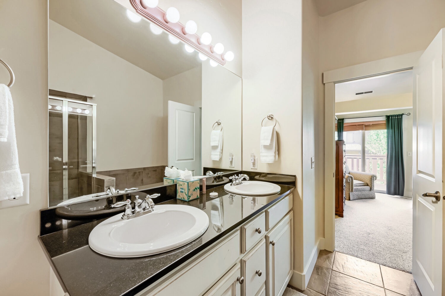 Freshen up in this bright bathroom featuring dual sinks and elegant vanity lighting—perfect for your morning routine before exploring the area.