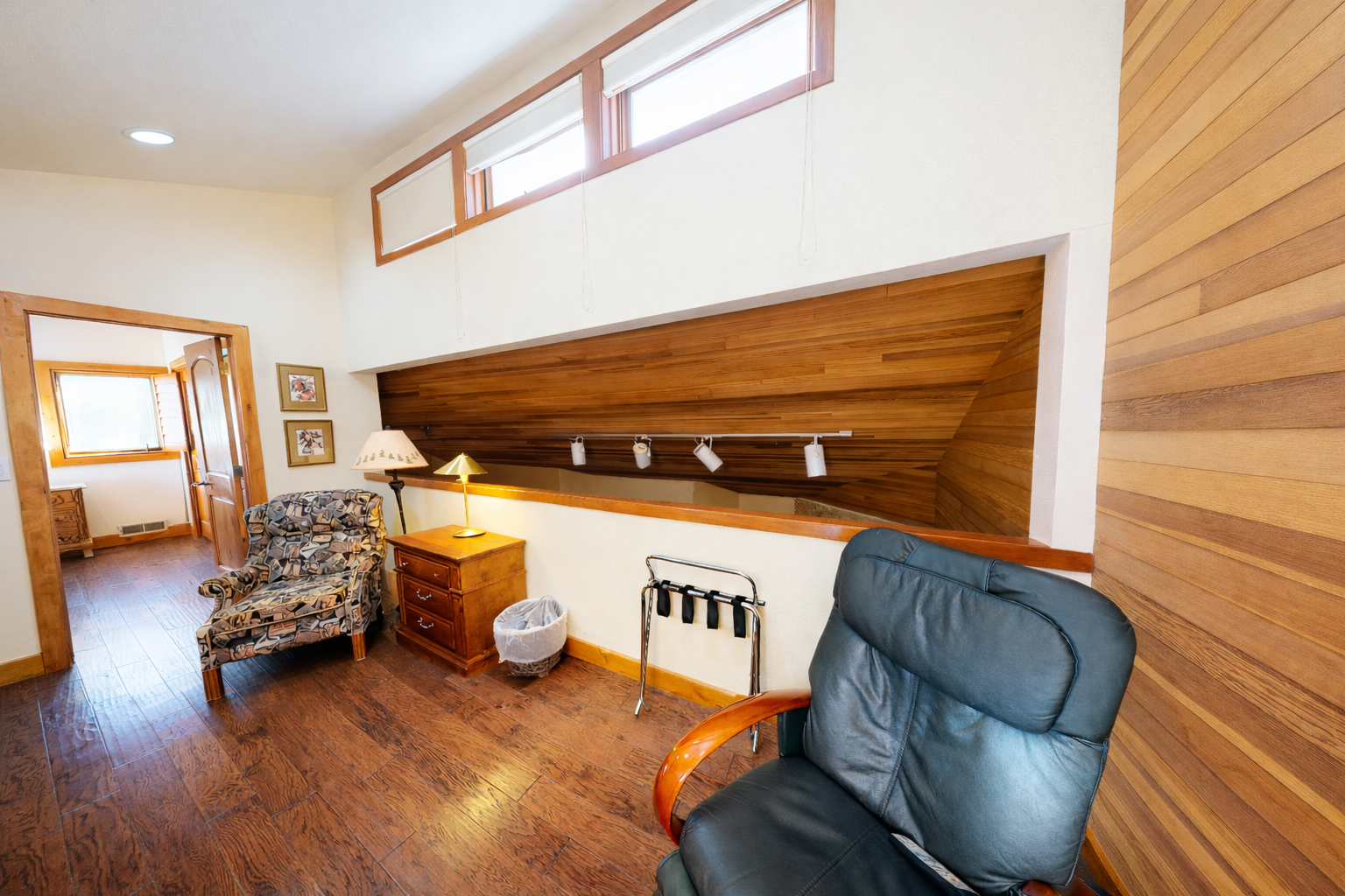 Relax in your spacious loft sitting room with soaring wooden ceilings, comfortable seating, and warm natural light streaming through clerestory windows above.