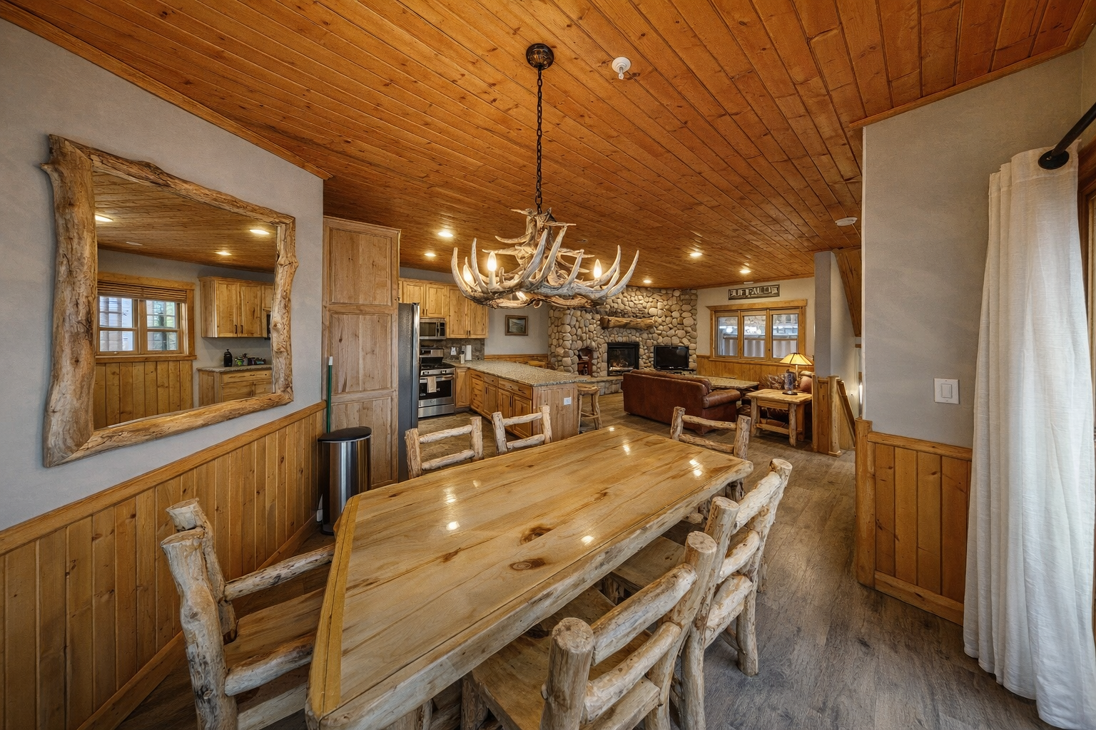 Gather around your rustic dining table where wood and stone create warmth under the stunning antler chandelier.