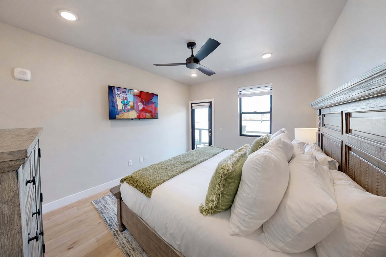 Relax in this bright, modern bedroom featuring a plush king bed and sleek wooden accents. A serene mountain retreat with large windows—perfect for your next Park City adventure.