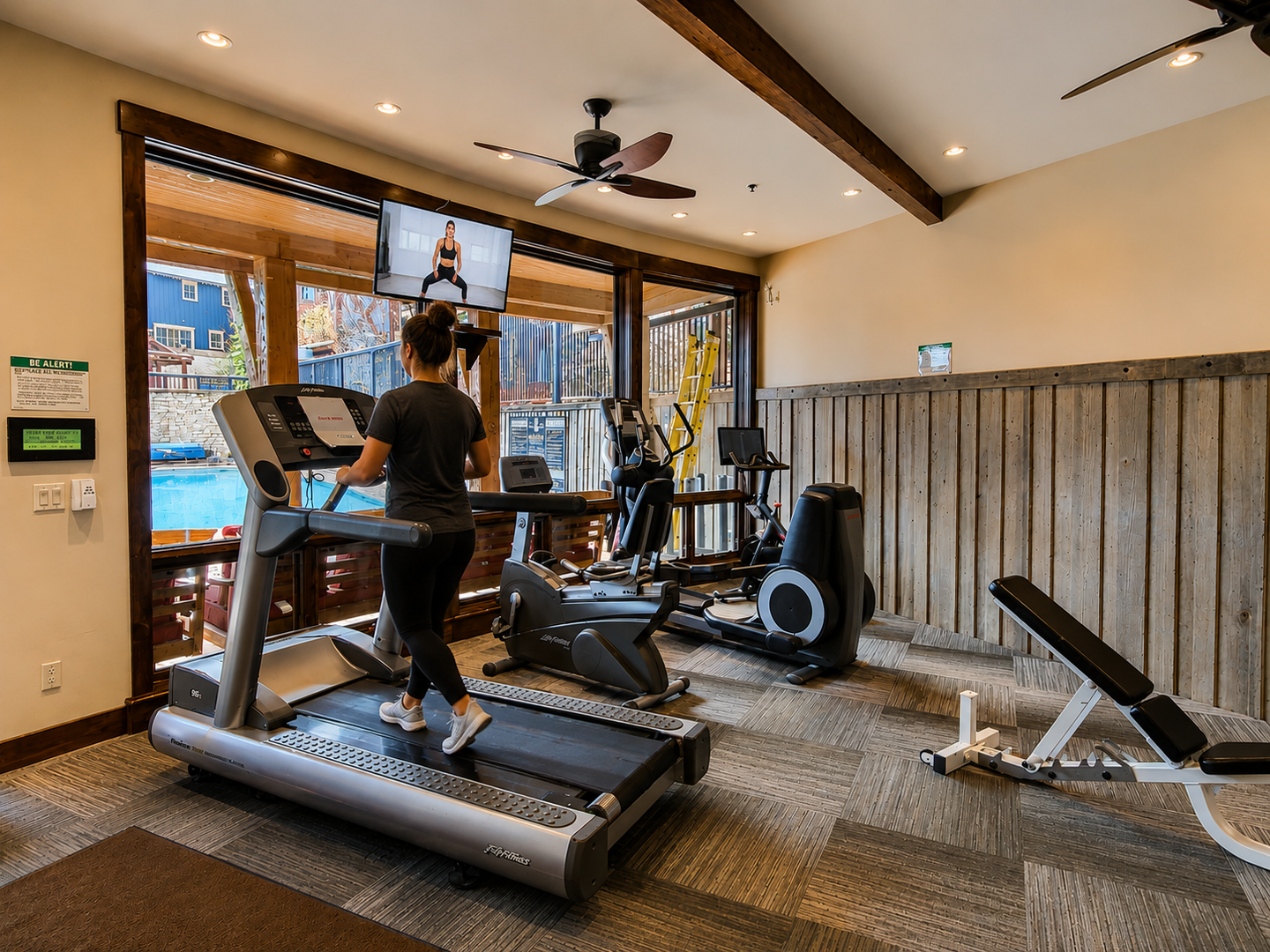 Stay on track with your fitness goals in this well-equipped gym featuring treadmills, ellipticals, weights, and a mounted screen for guided workouts—all with scenic pool views.