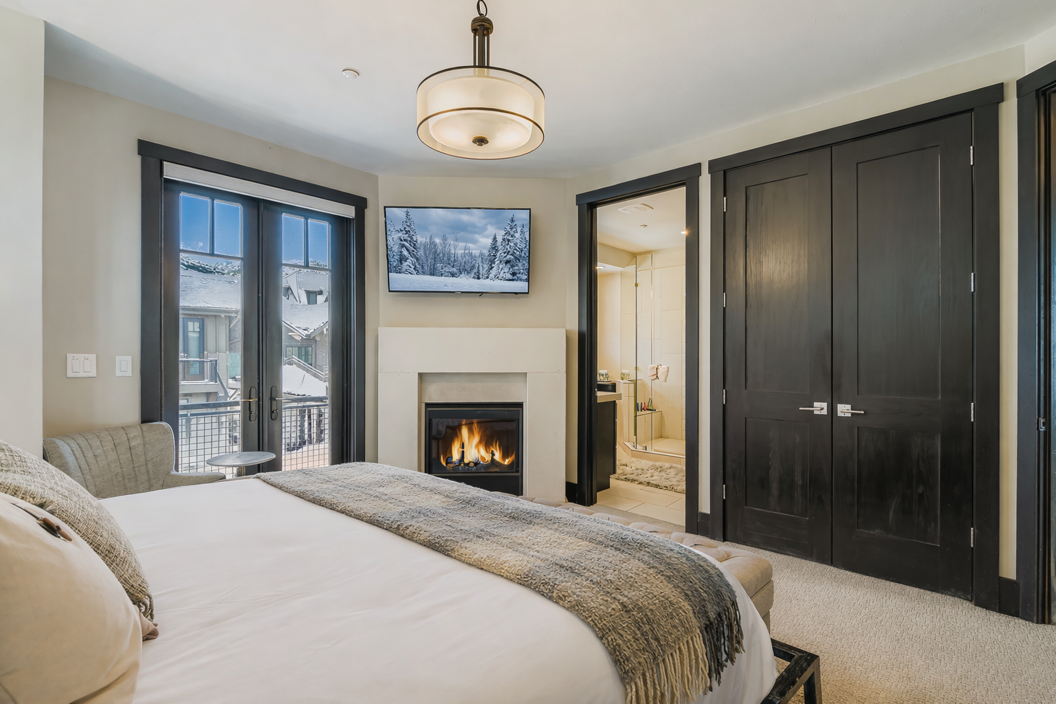 Relax in this bright, sophisticated primary suite featuring a plush king-sized bed, elegant tufted bench, and ample storage. Large windows offer natural light, creating a serene, stylish urban retreat.