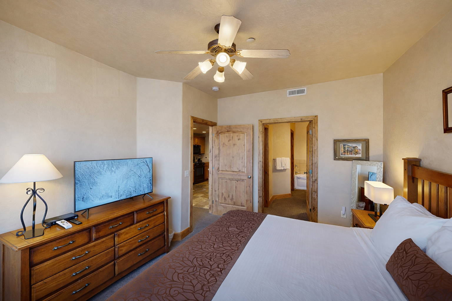 Unwind in your spacious bedroom with crisp linens, warm wood accents, and a ceiling fan to keep you comfortable year-round.