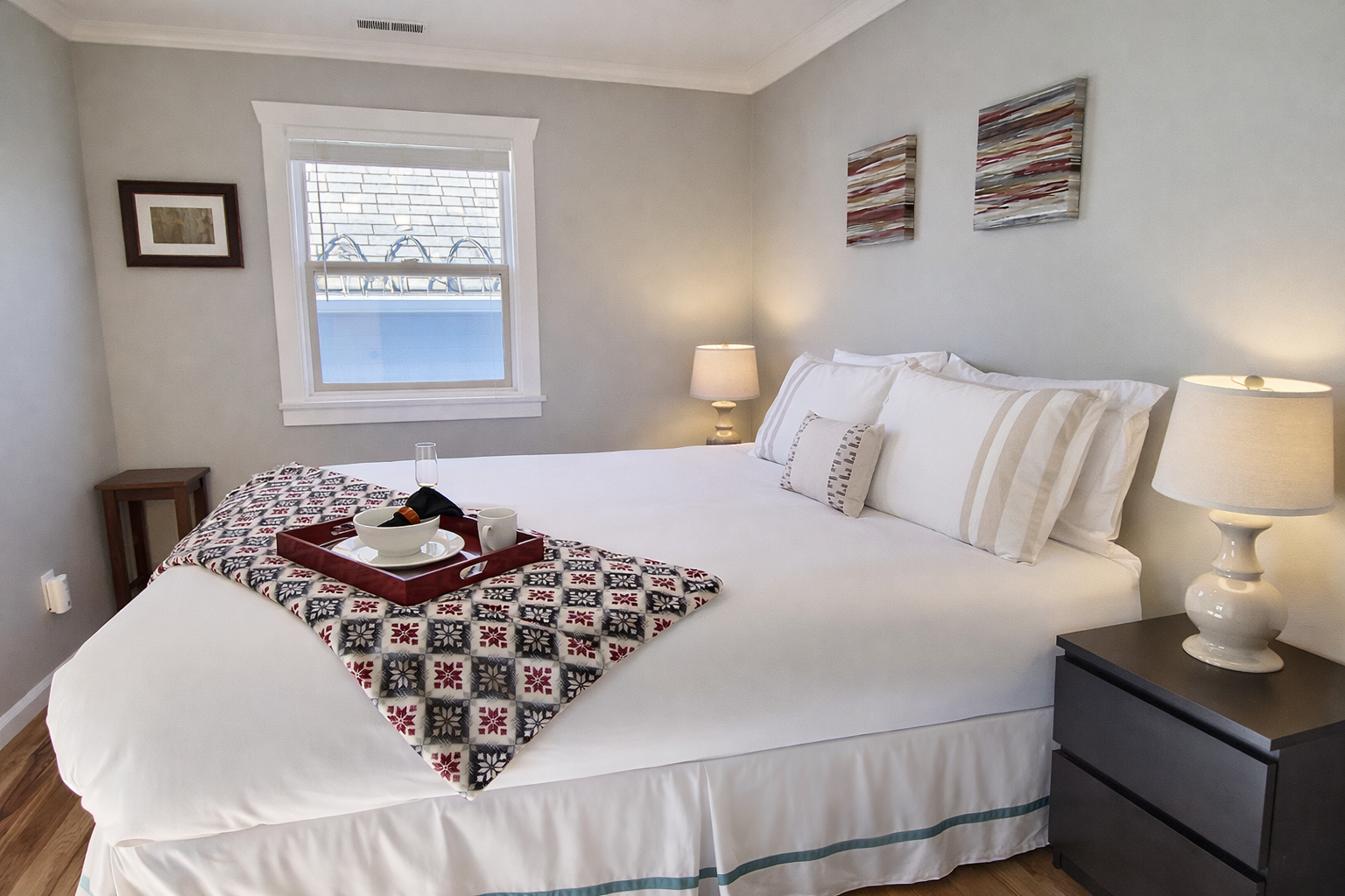 Sink into crisp white linens and enjoy morning coffee in this serene bedroom, where warm lighting and thoughtful touches create your perfect retreat.