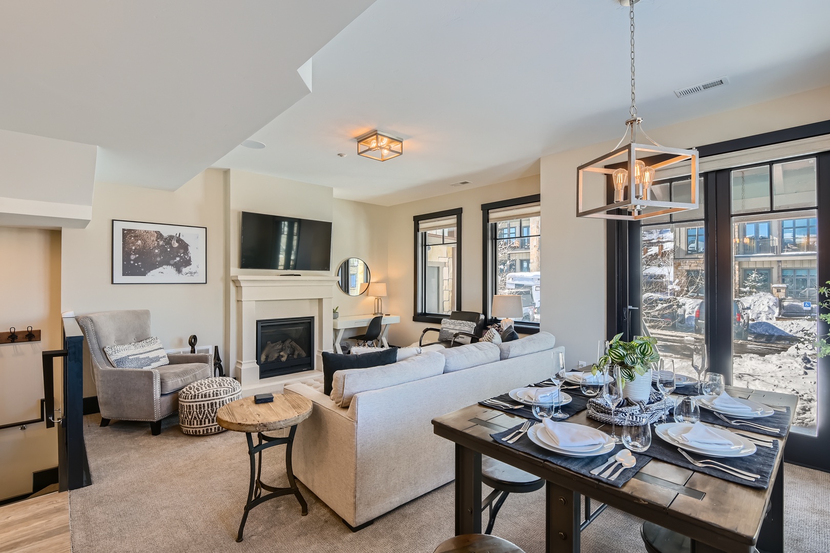 Step into your open-concept living space, where natural light fills the room through floor-to-ceiling windows. Gather around the fireplace after a day of adventure, or enjoy meals at the dining table beautifully set for your group.