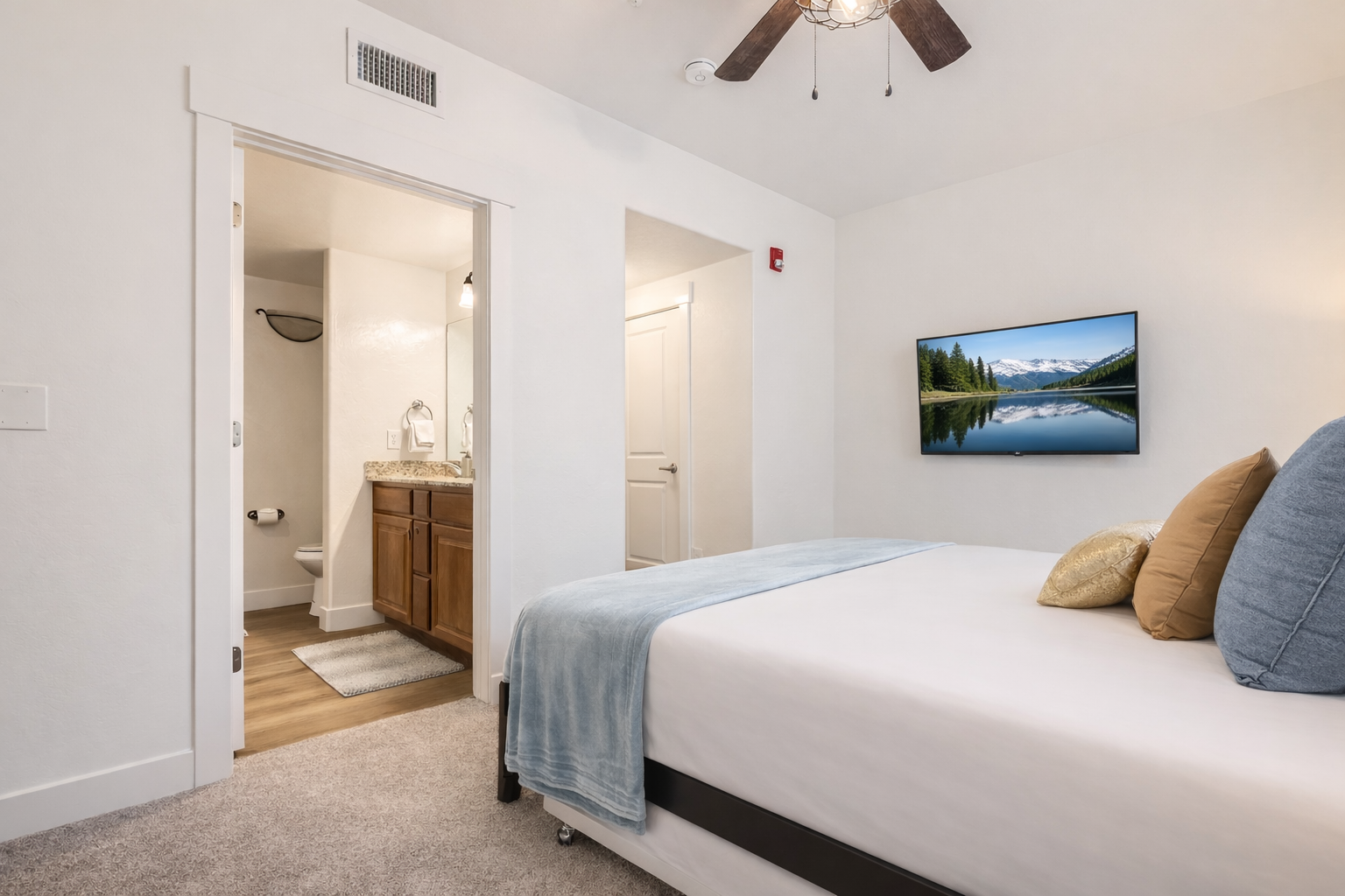 Relax in this bright, modern bedroom featuring a plush king-size bed, sleek dark wood furniture, and a large flat-screen TV. A serene mountain retreat for your next Park City adventure.