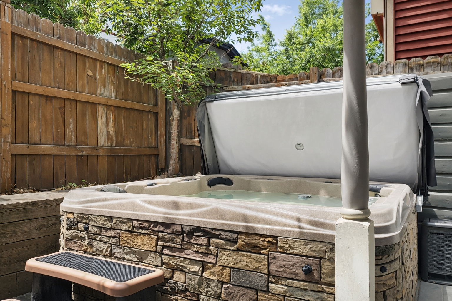 Your private hot tub awaits in this secluded backyard oasis, surrounded by natural stonework and mature trees for ultimate relaxation.