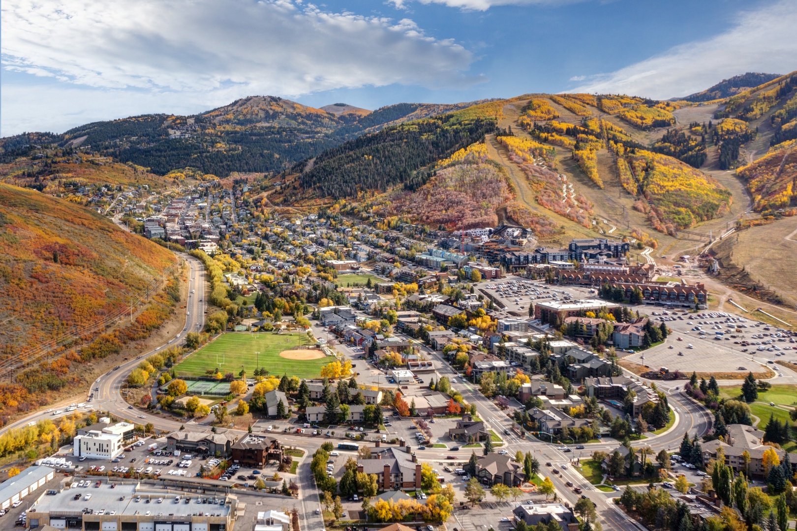Aerial view of a mountain town nestled in a valley surrounded by autumn foliage and ski slopes during fall season.