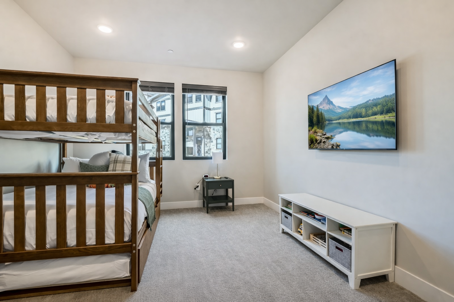 Host large groups in this modern Park City bunk room featuring a triple-tier bed, sleek grey dresser, and bright windows. The perfect year-round family alpine retreat!
