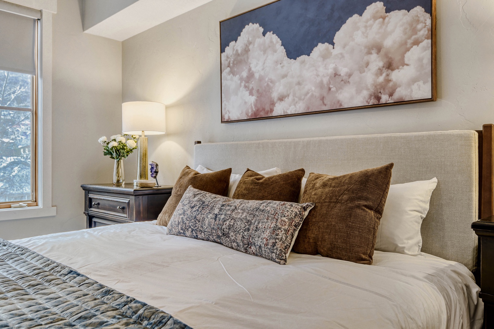 Sink into plush bedding beneath dreamy cloud artwork in your serene bedroom sanctuary, where natural light and elegant touches create perfect relaxation.