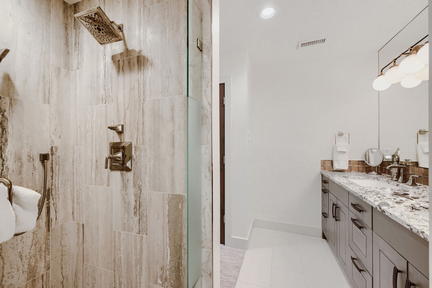 Your private spa-like bathroom features a spacious walk-in shower with elegant wood-look tile and gleaming bronze fixtures, plus a double vanity with sparkling granite countertops for all your morning rituals.