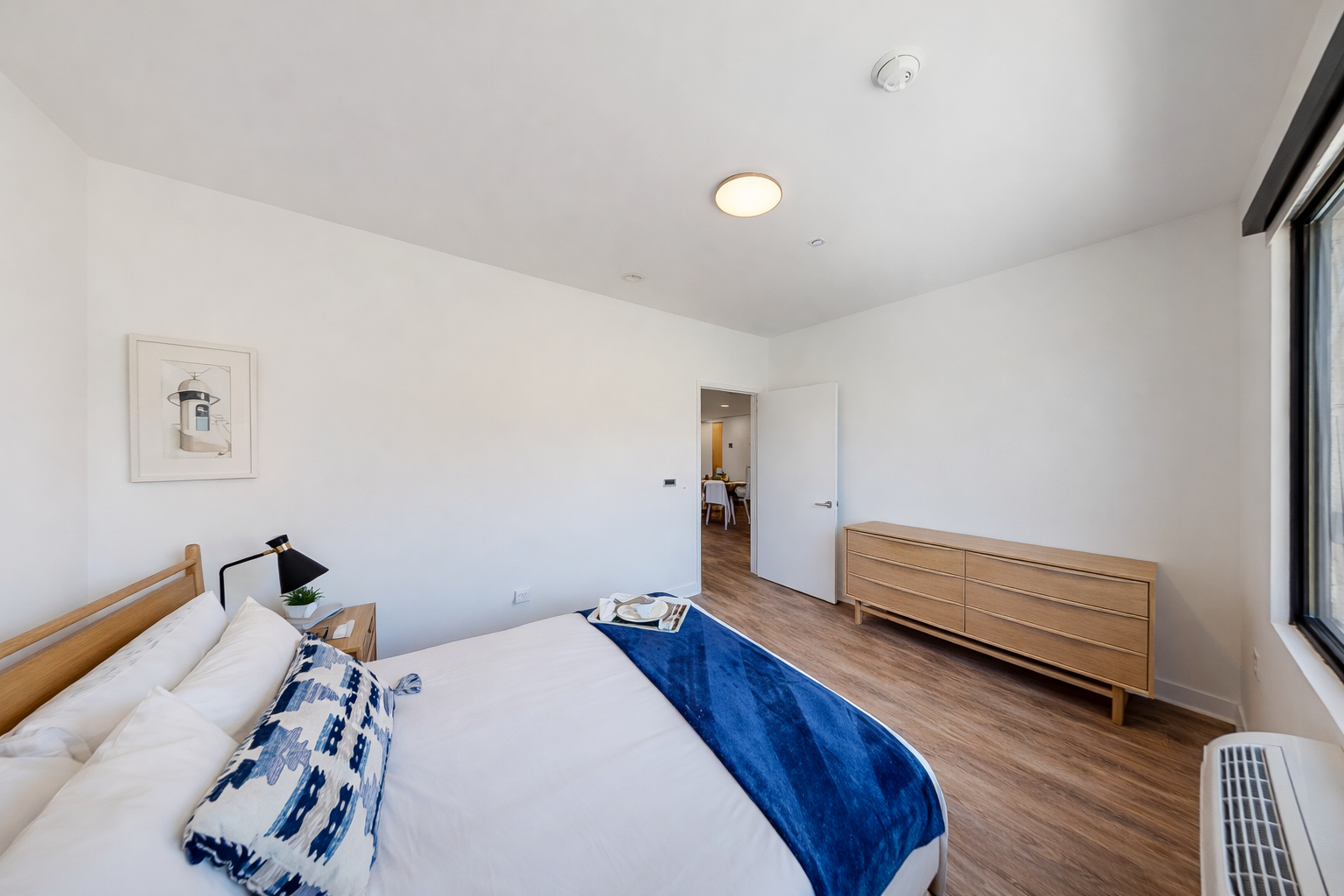 Unwind in your serene bedroom featuring crisp white linens with vibrant blue accents and warm wood furnishings.