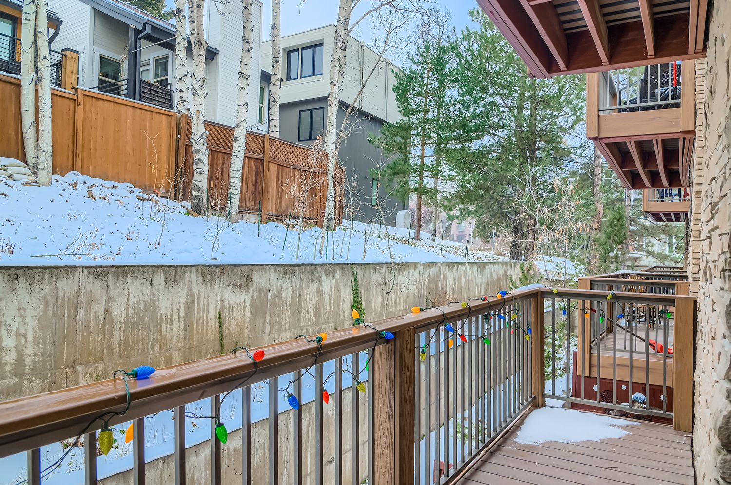 Step out onto your private balcony where festive lights create a cheerful atmosphere, offering views of the peaceful snowy neighborhood and surrounding trees.