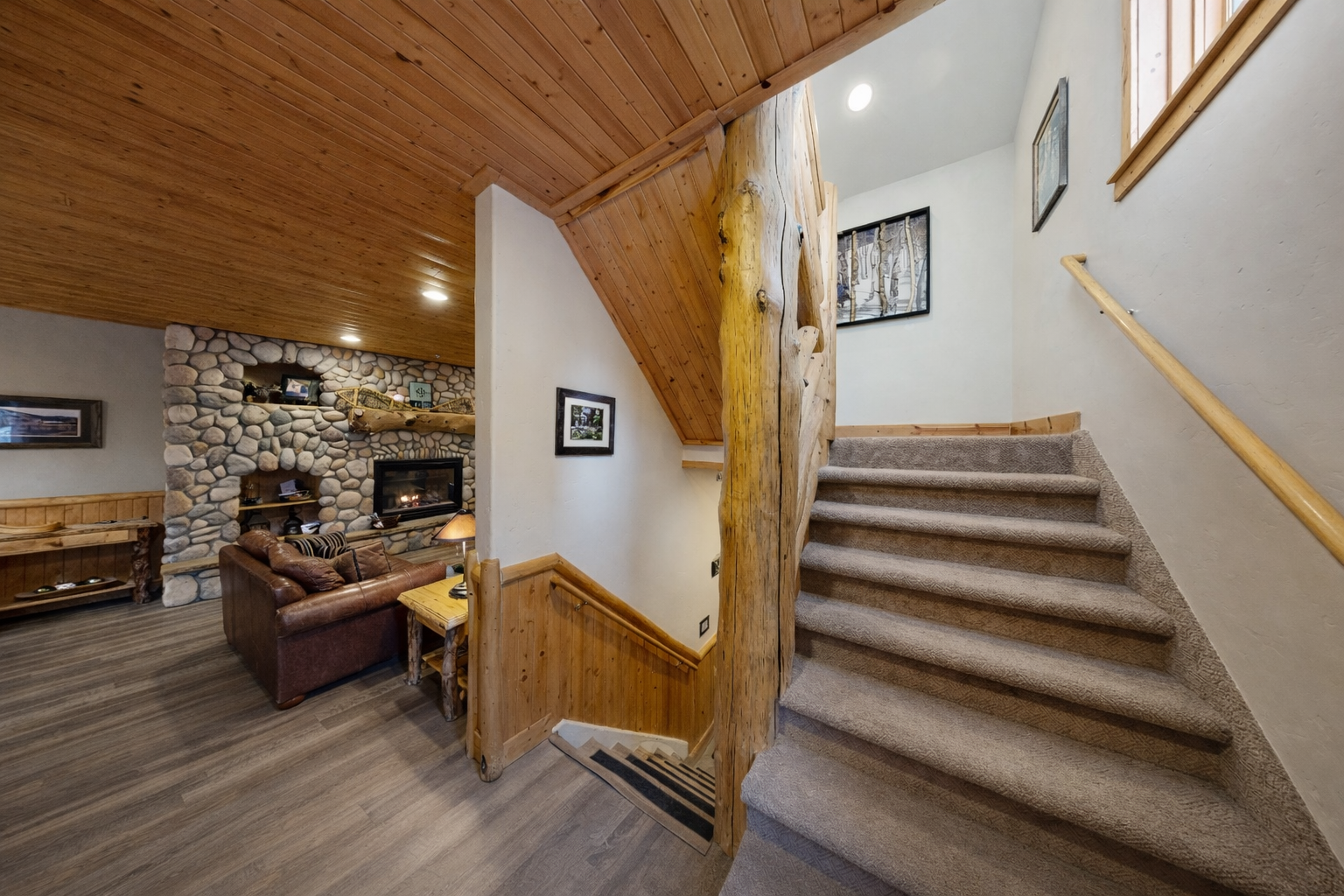 Cozy rustic charm awaits you with exposed beams, stone fireplace, and comfortable seating creating the perfect mountain retreat atmosphere.