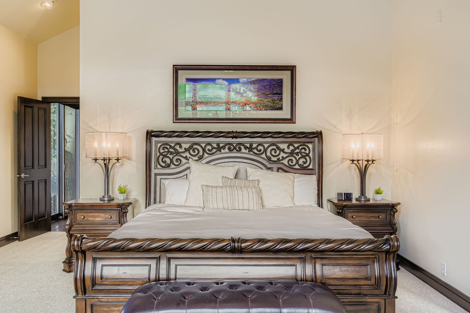 Sink into the luxurious king bed with its ornate metal headboard, surrounded by elegant nightstands and soft ambient lighting for your perfect night's rest.