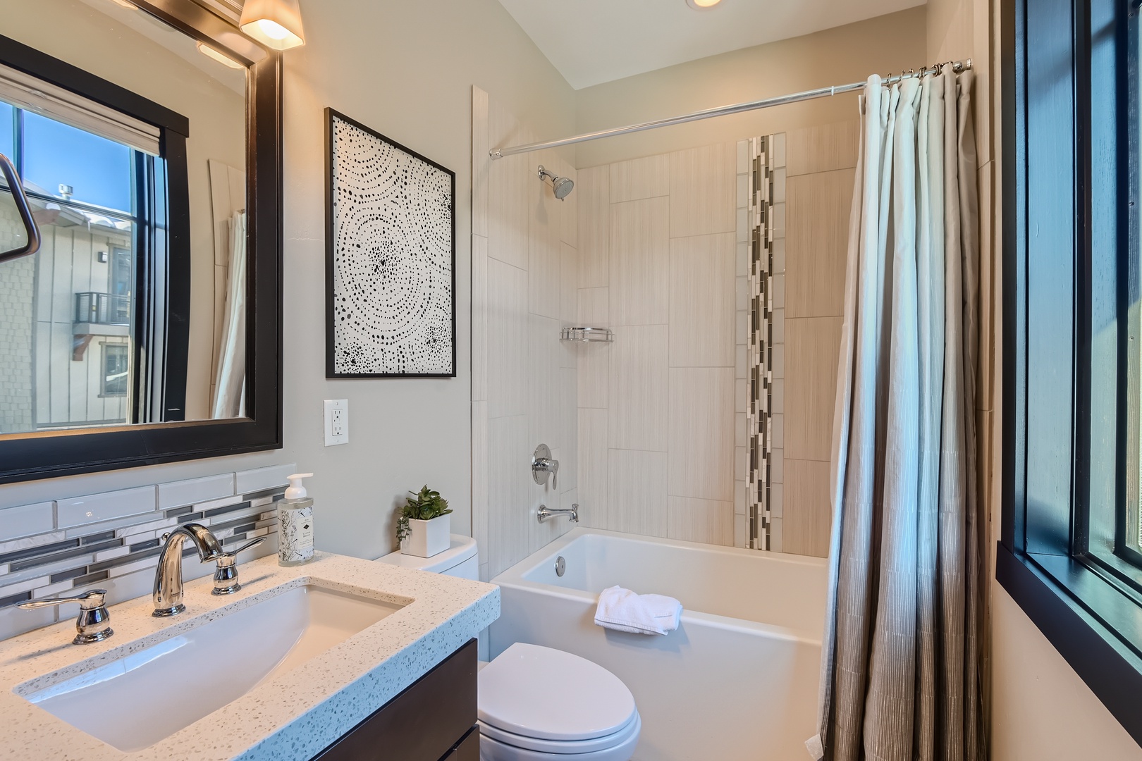Freshen up in your modern bathroom, complete with a luxurious tub-shower combo, sleek vanity, and natural light streaming through large windows.