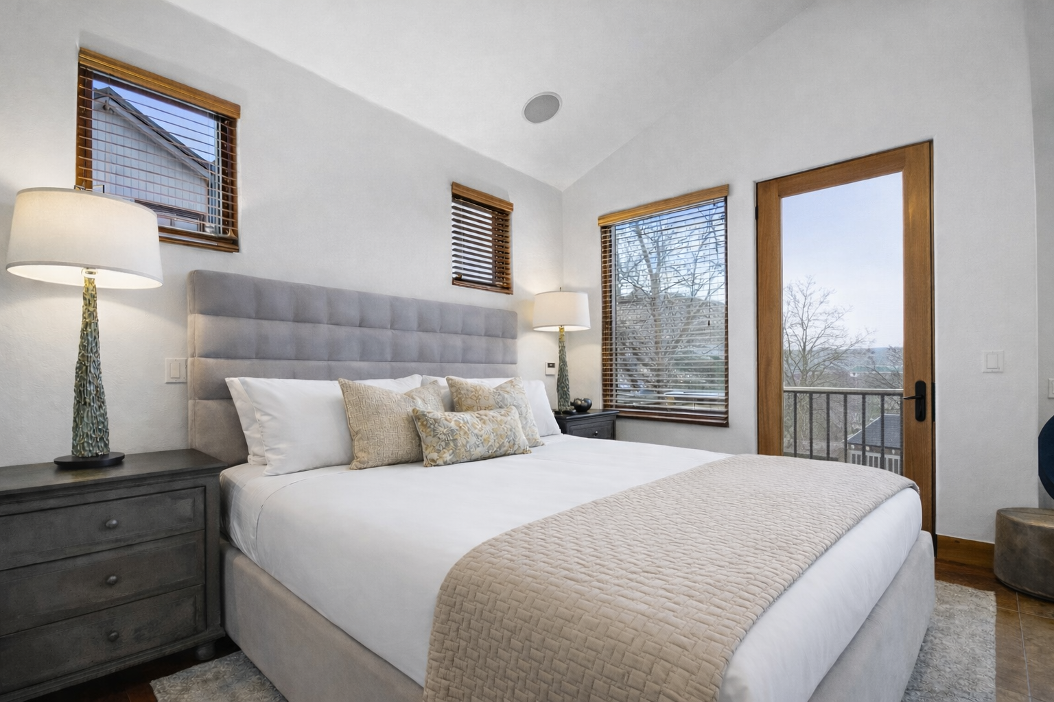 Sink into crisp white linens in your serene bedroom, where warm wood blinds filter gentle light and your private balcony beckons for morning coffee.