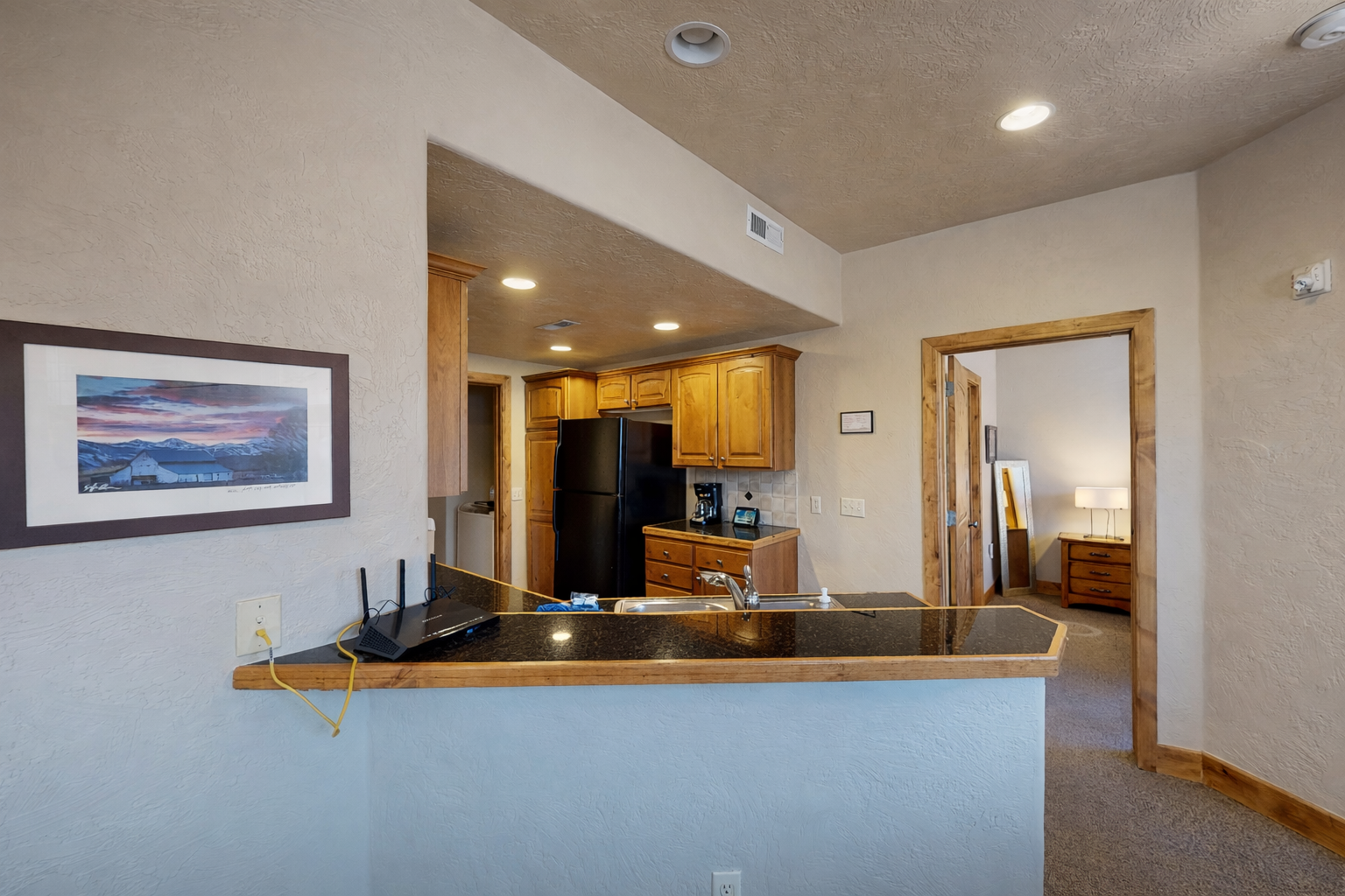 Your open kitchen features granite countertops, modern appliances, and warm wood cabinetry, perfect for preparing meals..