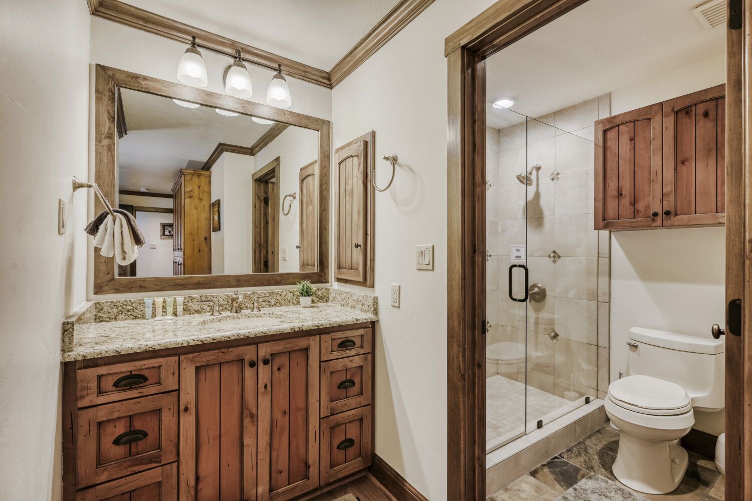 Unwind in your rustic-chic bathroom with granite countertops, custom wood cabinetry, and a spacious glass shower.