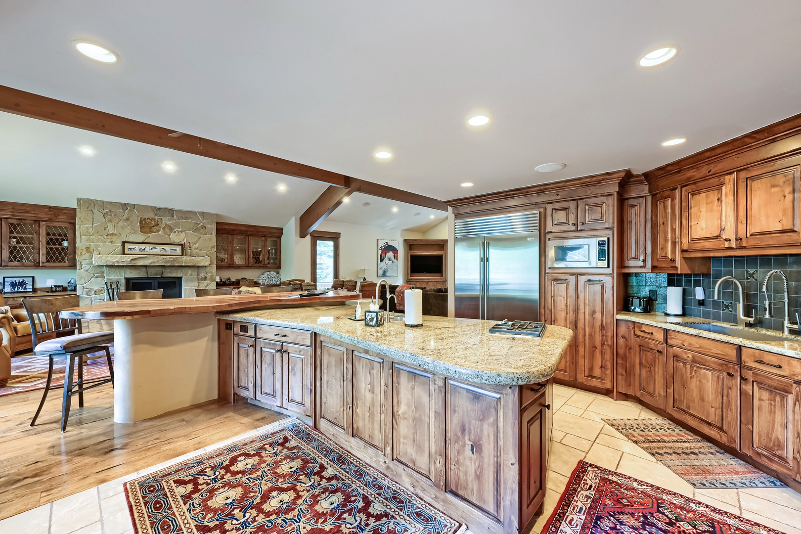 Your fully equipped gourmet kitchen with granite countertops, rich wood cabinetry, and stainless steel appliances invites you to create memorable meals in this spacious, naturally lit gathering space.