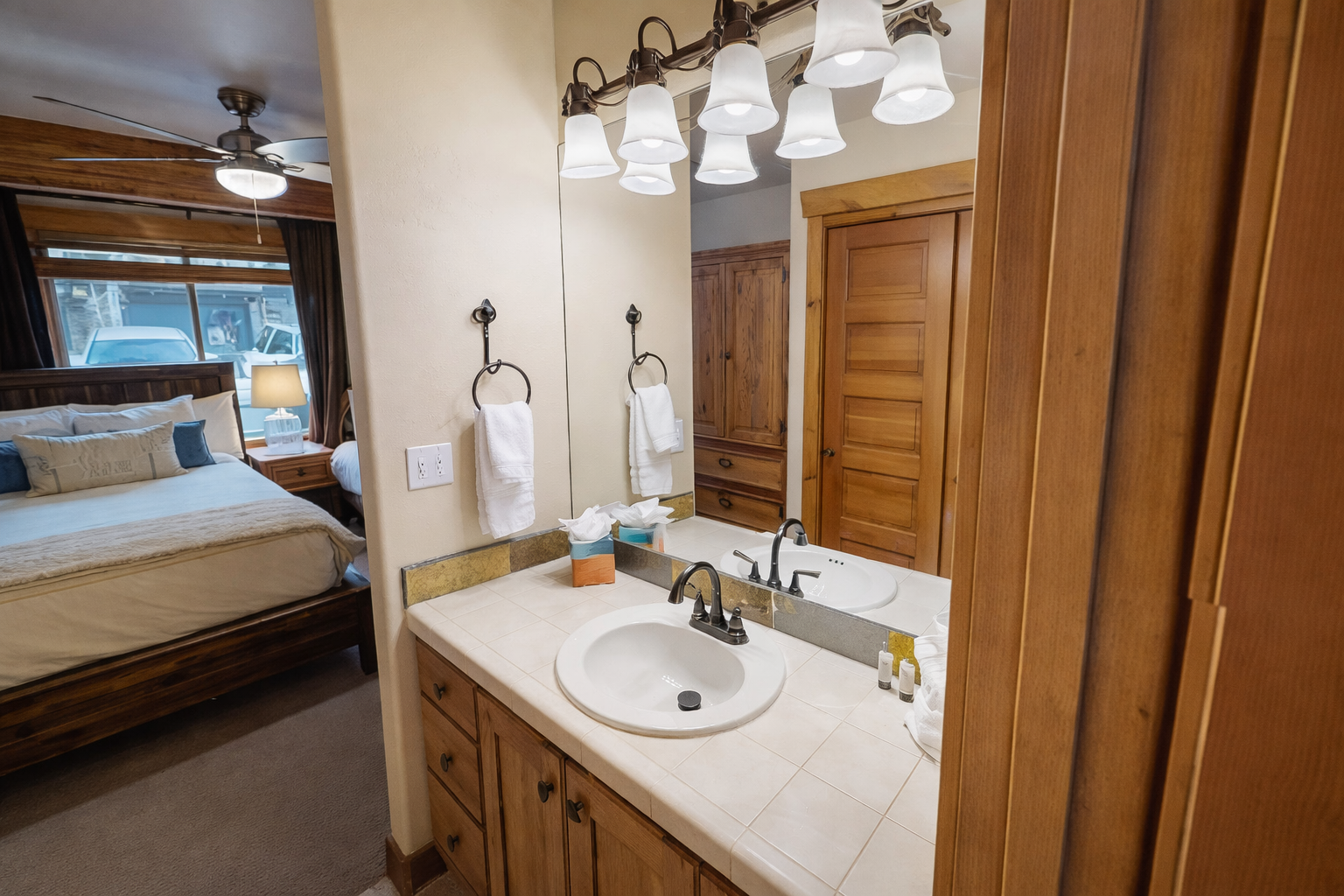 Your ensuite bathroom offers warm wood cabinetry and fresh towels, perfectly positioned between bedroom and wardrobe for effortless mornings.