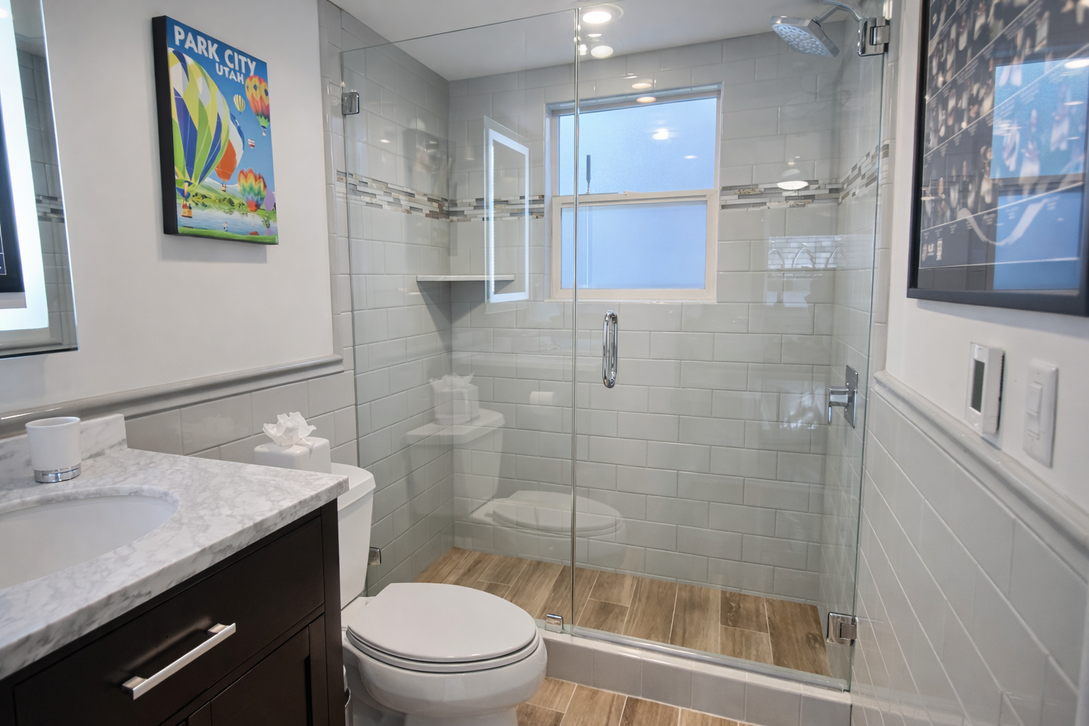 Step into your spa-like bathroom with a stunning glass-enclosed shower, marble countertops, and warm wood-look flooring for ultimate relaxation.