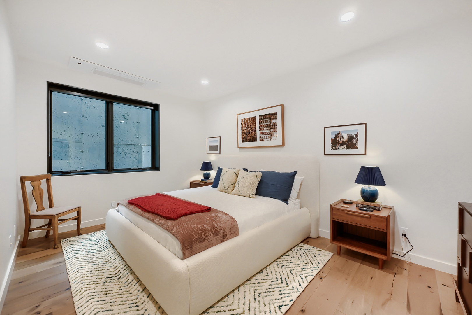 Slip into crisp white linens and wake up refreshed in this peaceful bedroom, where warm wood floors and natural light create your perfect retreat.