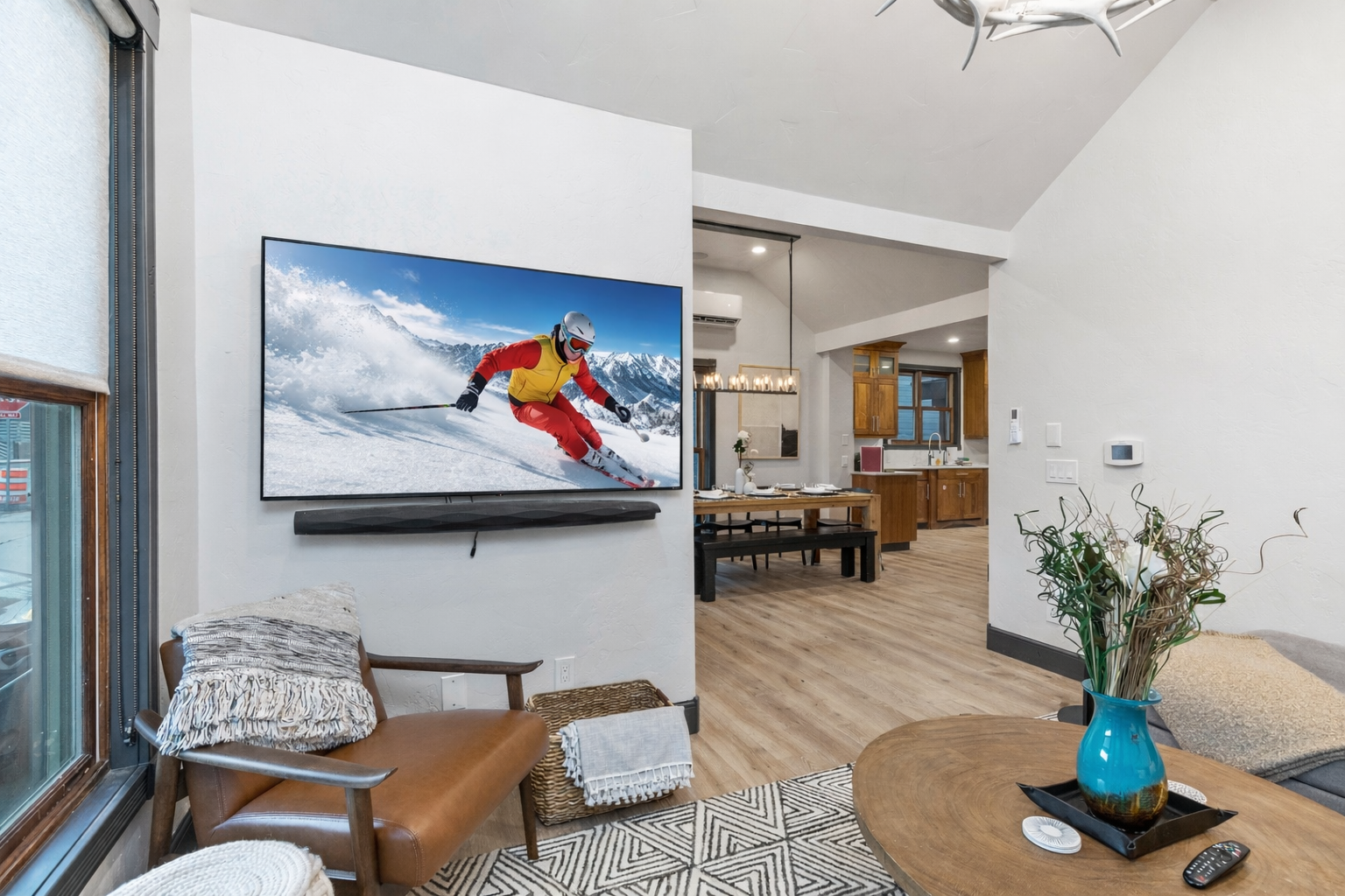 Unwind in the bright, vaulted living room with a spacious sectional, modern decor, and charming views into the chef's kitchen. The perfect cozy spot to relax.