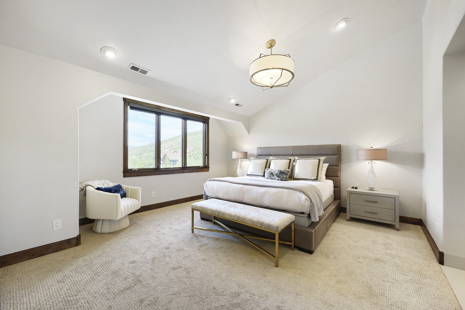 Drift off in this tranquil bedroom, where soft linens and a plush upholstered bench invite you to unwind. Wake to stunning mountain views framed by sleek windows that fill the space with natural light.