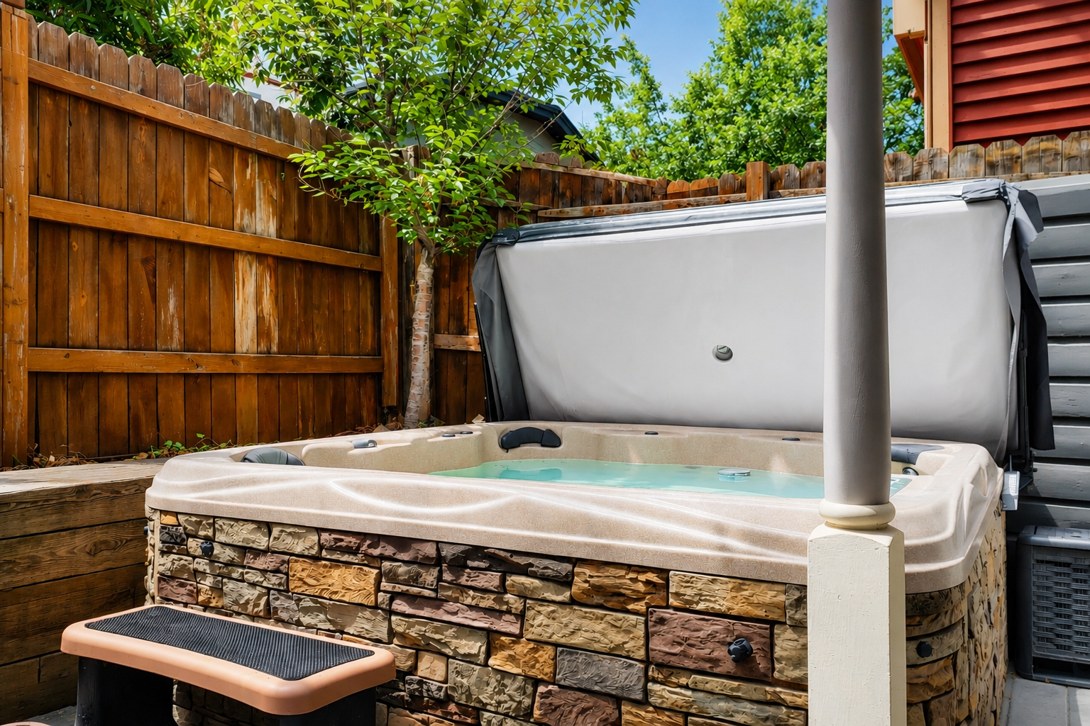 Slip into the private hot tub surrounded by lush greenery and wooden fencing for your ultimate secluded outdoor retreat under the open sky.