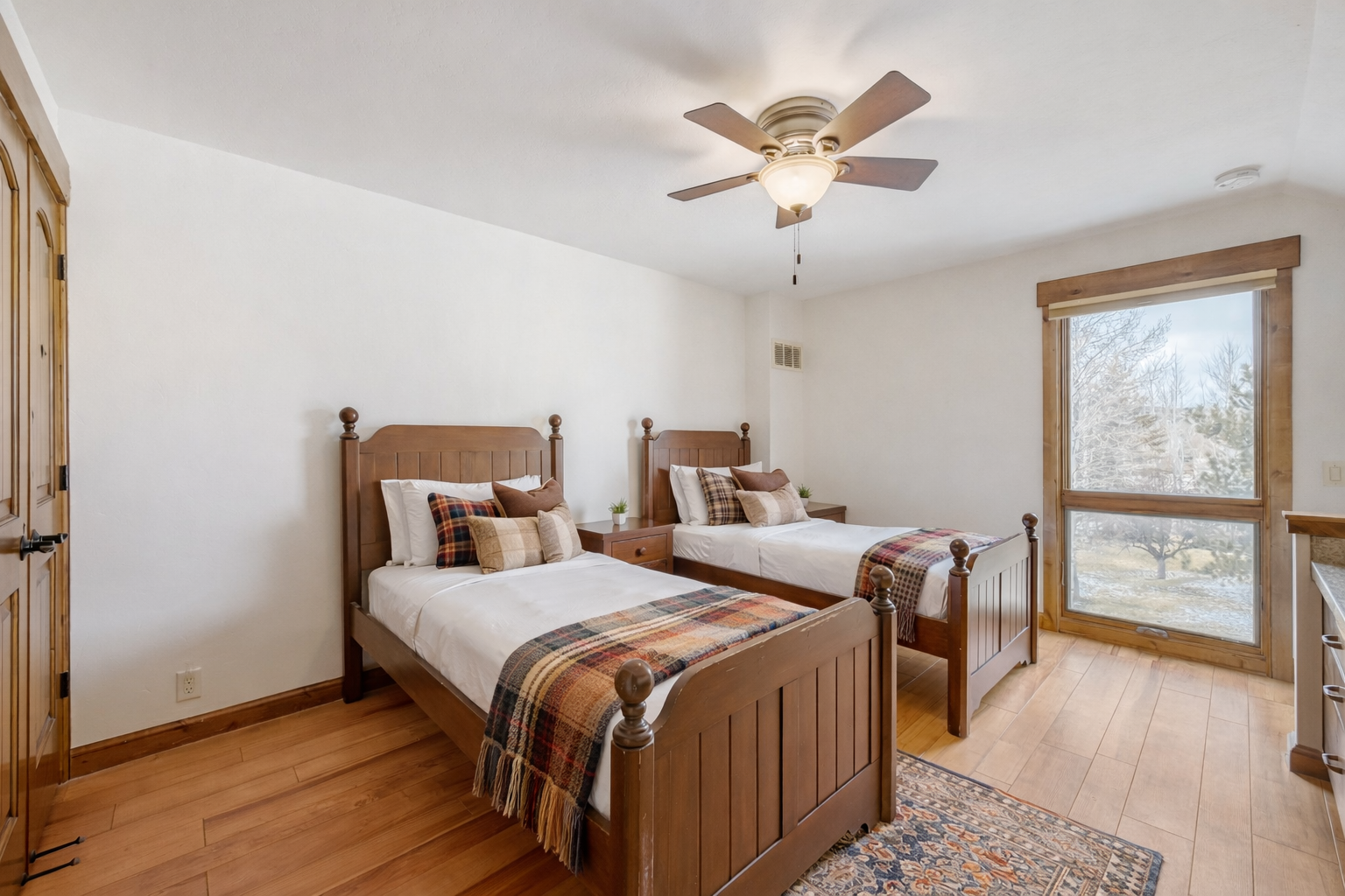 Your cozy twin bedroom features rustic wooden beds with warm plaid accents and peaceful views to help you unwind after exploring.