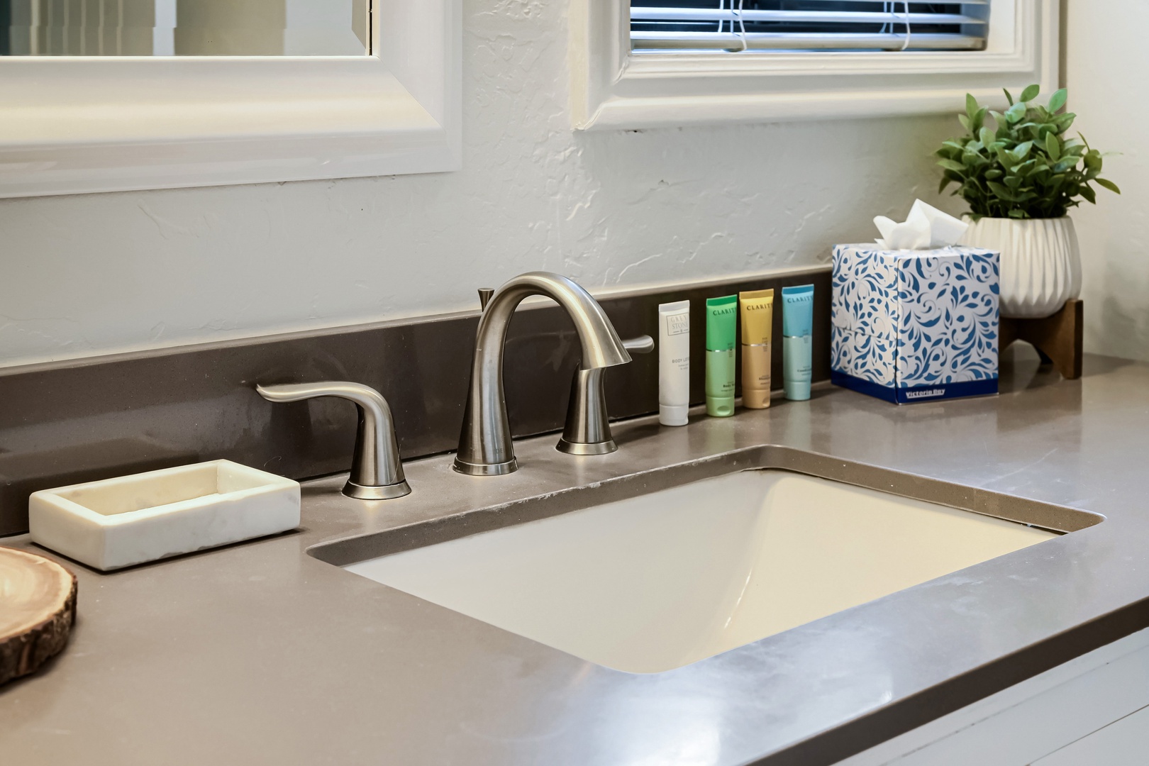 Step into your private bathroom featuring a sleek countertop, modern fixtures, and thoughtful touches—from quality toiletries to a fresh plant. Your peaceful morning routine starts here.