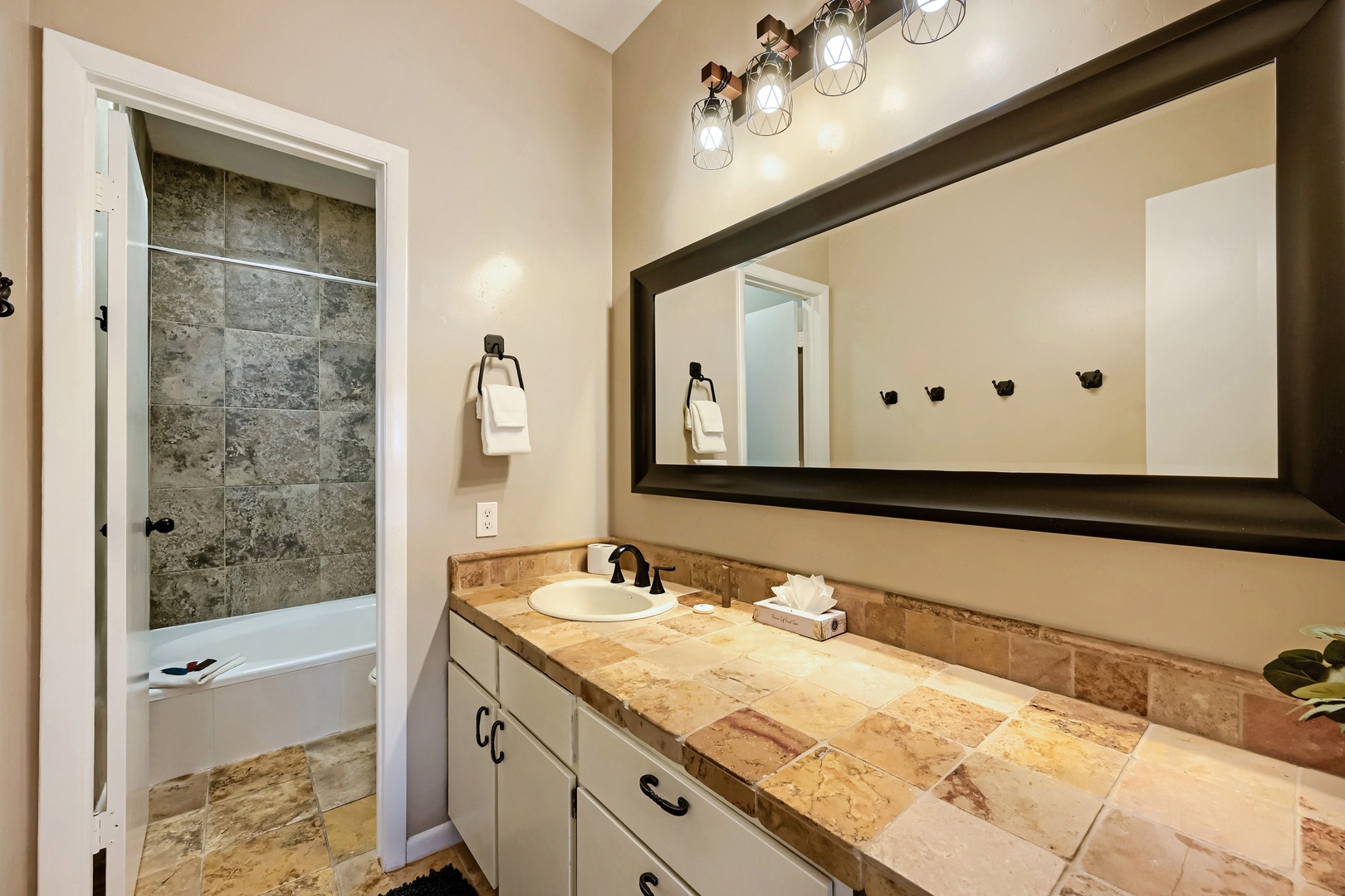 Step into your private bathroom, where warm lighting illuminates elegant tile and a spacious vanity awaits your morning routine. The tub-shower combination offers relaxation after your day's adventures.