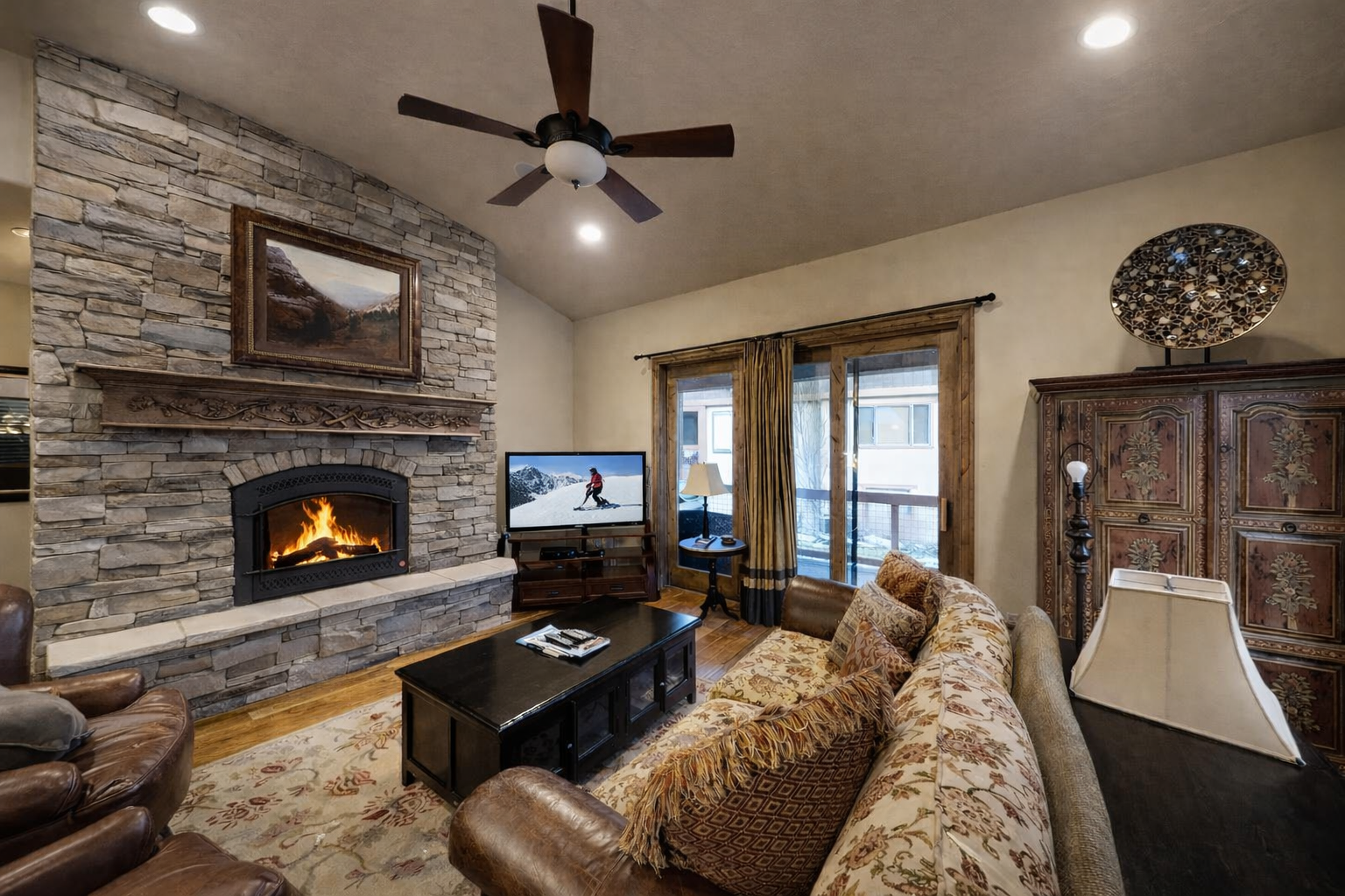 Relax in this cozy mountain retreat featuring a warm stone fireplace, plush seating, and rustic-chic decor. Enjoy a movie on the flat-screen or step onto the balcony for fresh air.