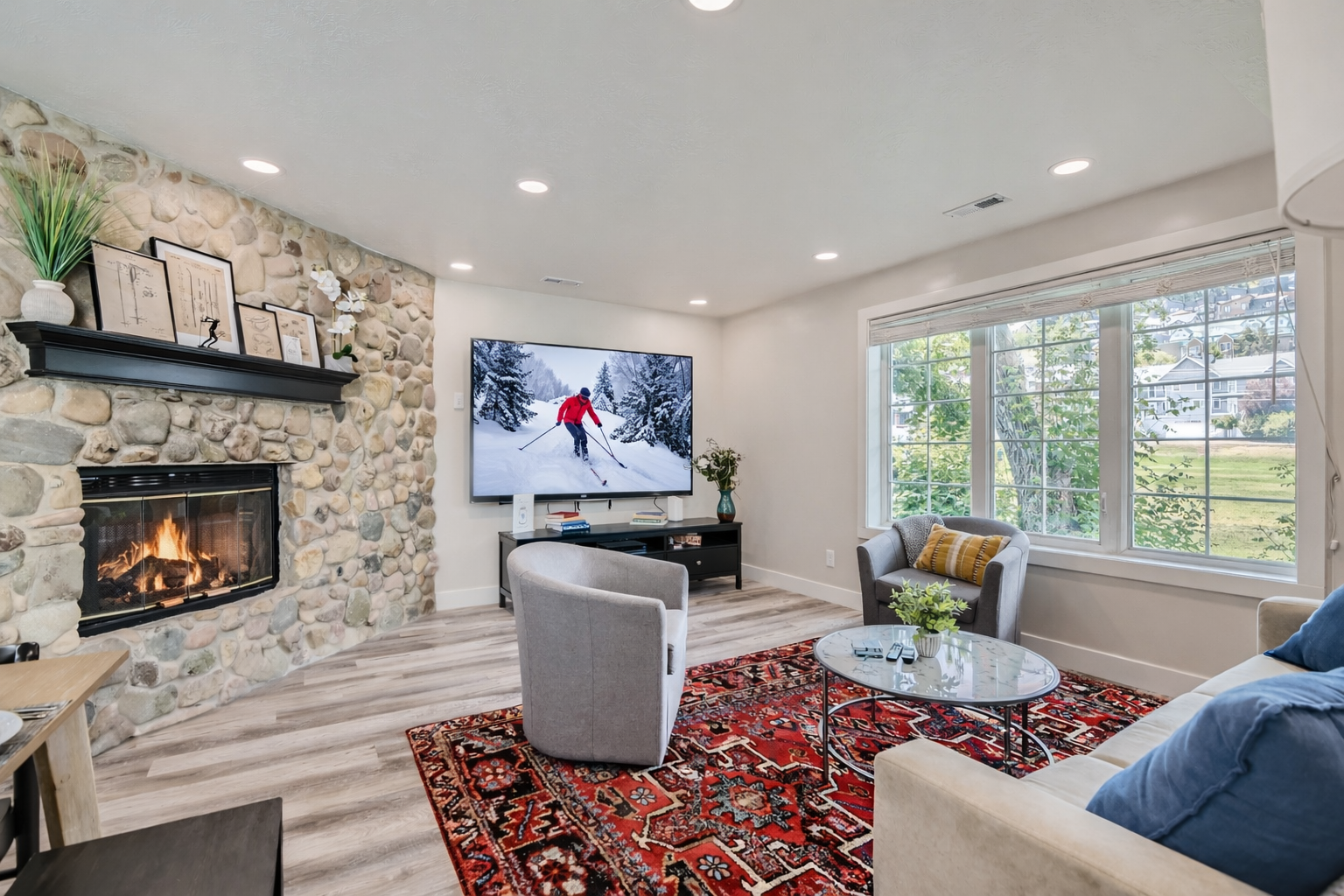 Unwind in the inviting living area featuring a stunning stone fireplace, comfortable seating including a chic accent chair, and a stylish marble-top coffee table.