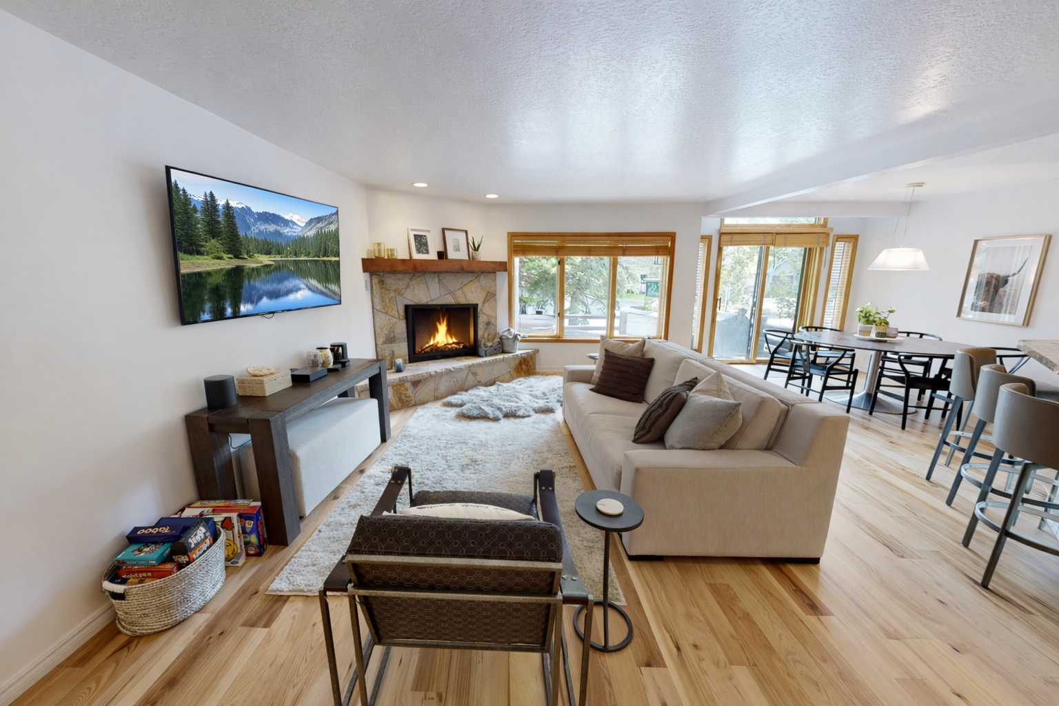 This spacious living room features a cozy fireplace and large windows offering scenic mountain views. Relax on the comfortable sectional while enjoying the tranquil atmosphere.