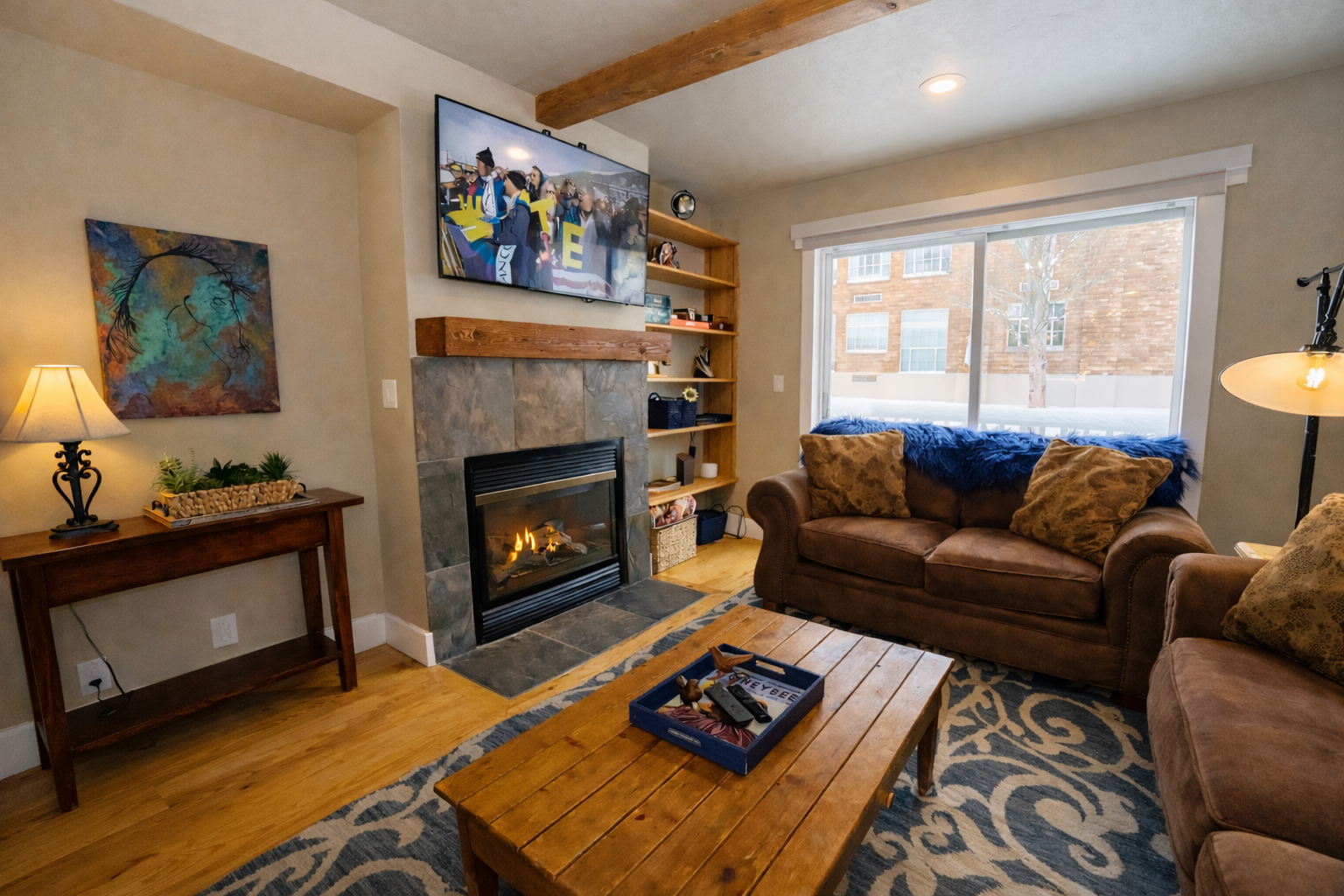 Unwind in your cozy living room where warm firelight dances across rich leather sofas and rustic wood beams frame mountain views.