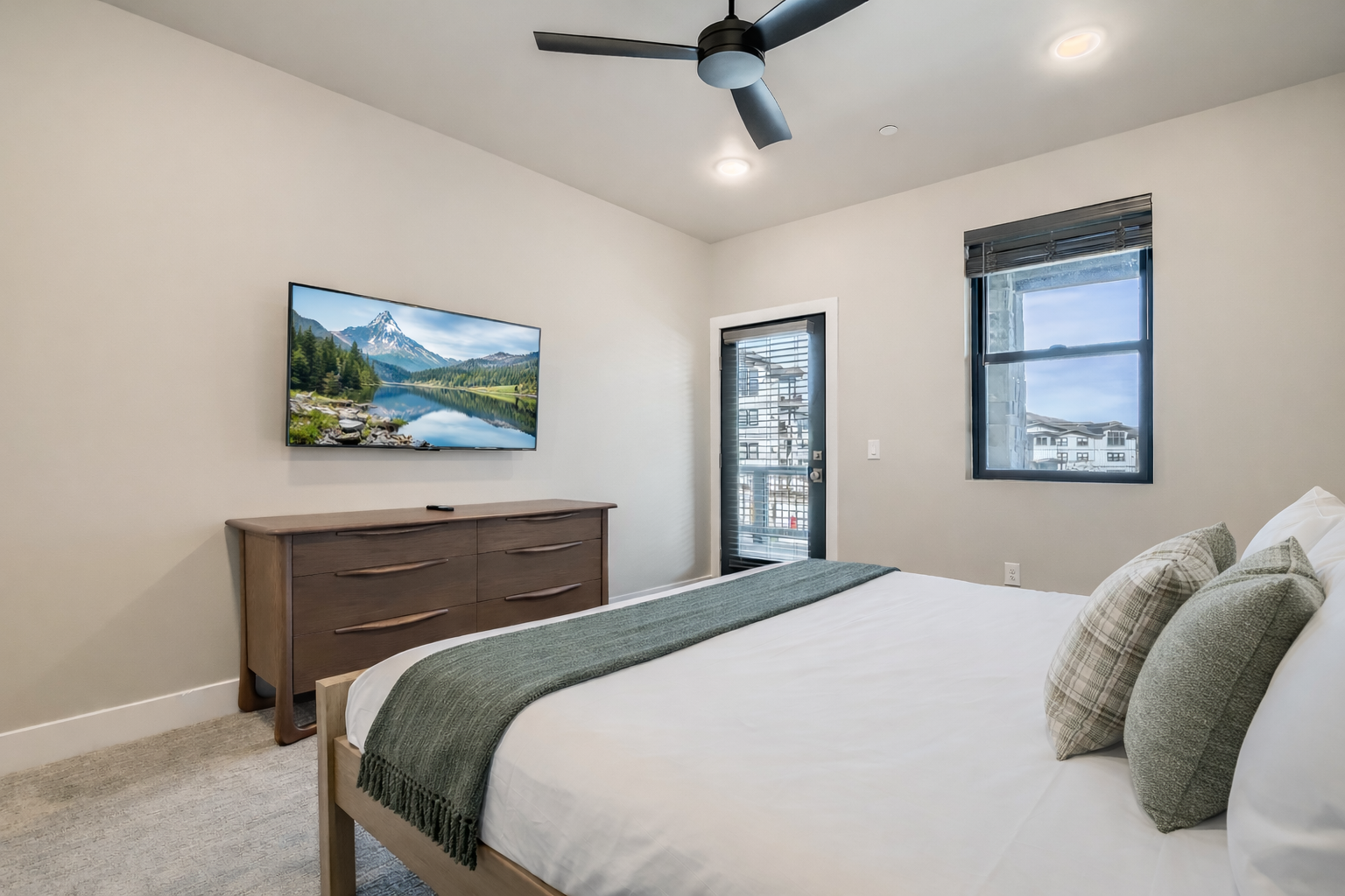 Relax in this bright, modern bedroom featuring a plush king bed and sleek wooden accents. A serene mountain retreat with large windows—perfect for your next Park City adventure.