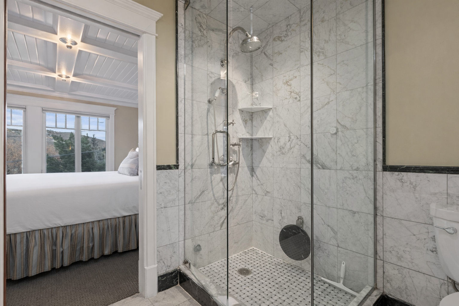 Step into luxury with your elegant glass-enclosed shower featuring marble-pattern walls and mosaic flooring—pure relaxation awaits in this sophisticated ensuite.