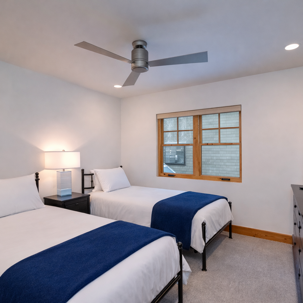 Retire to the quiet third floor twin bedroom, featuring two comfortable beds, a ceiling fan, and natural light. It's the perfect escape after a busy day.