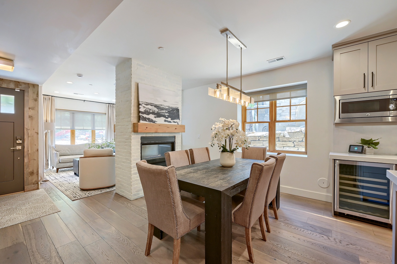 Gather around this elegant dining table where you'll share meals beneath a modern chandelier, with mountain views framing your moments and a cozy fireplace nearby for warmth.