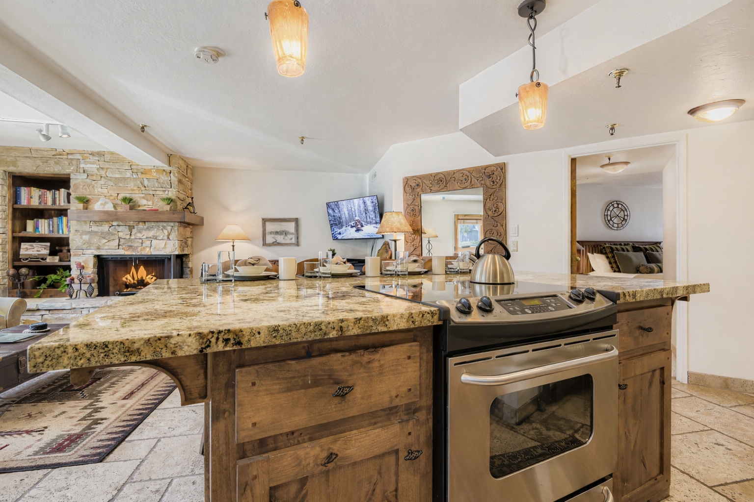 A fully equipped kitchenette with rustic wood cabinetry, granite countertops, and stainless steel appliances.