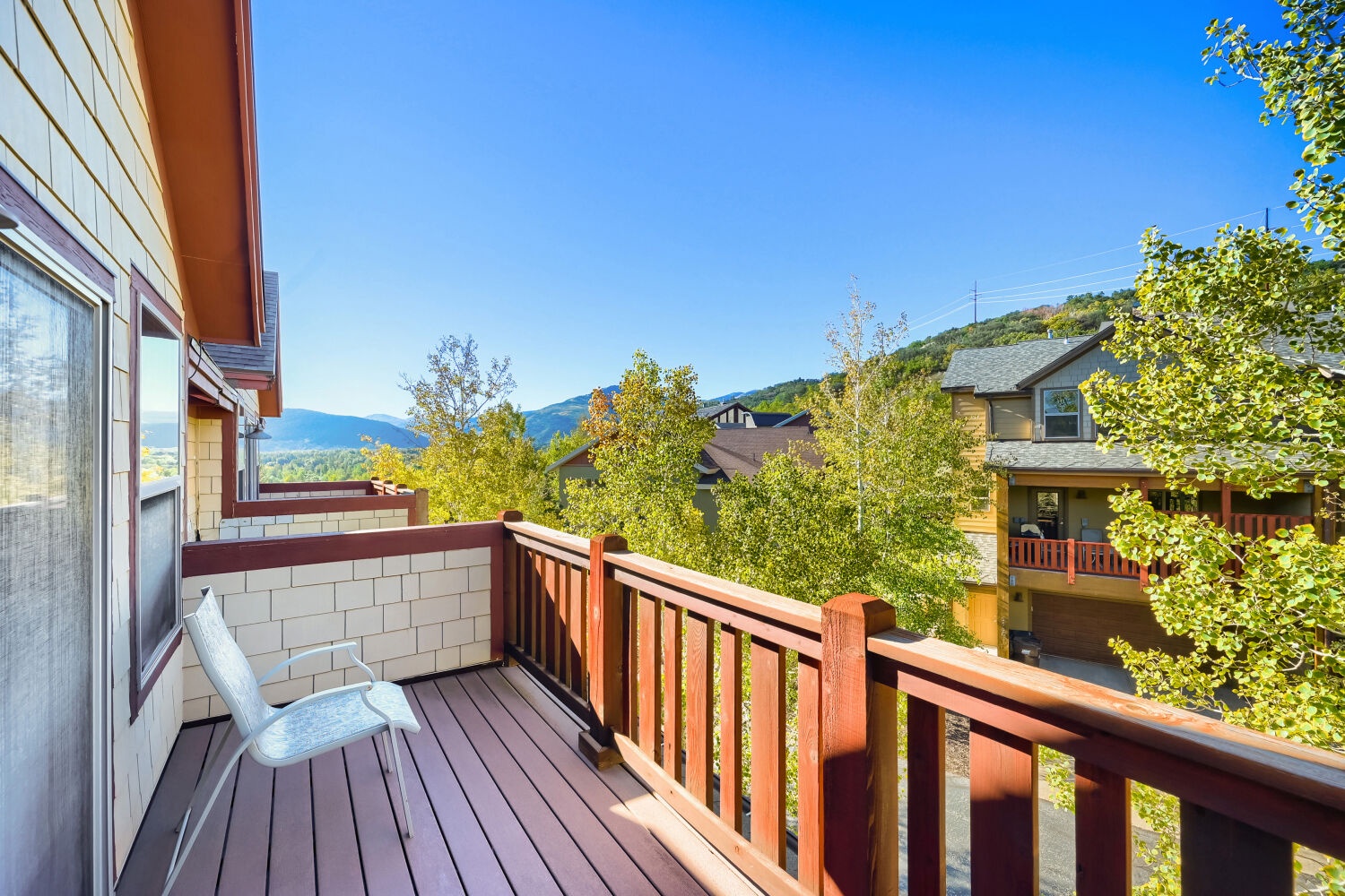 Step onto your private balcony and breathe in the fresh mountain air while taking in the sweeping views of rolling hills and neighboring rooftops under bright blue skies.