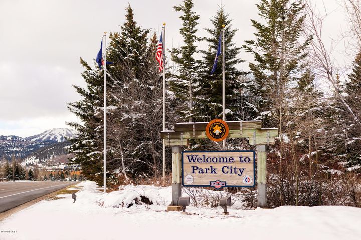 Welcome to Park City entrance sign surrounded by snow-covered evergreen trees and mountain views in winter.