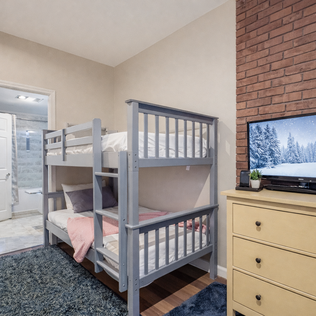 Your cozy bunk bedroom features comfortable sleeping for multiple guests, complete with entertainment and charming exposed brick details.