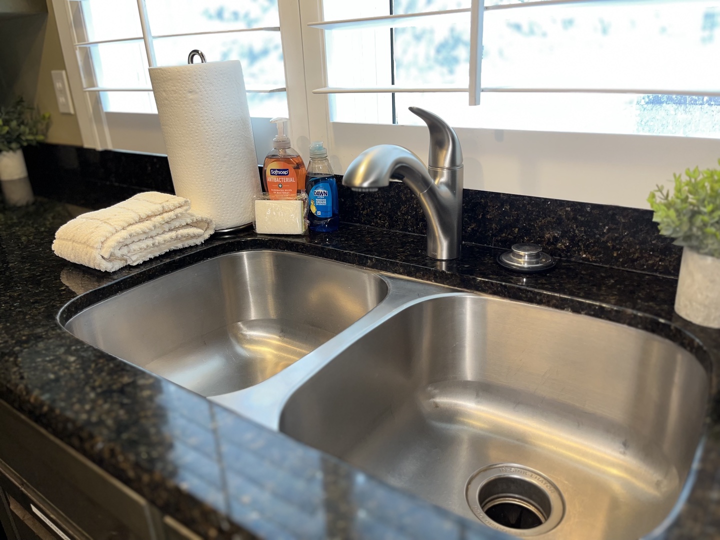 This double-basin stainless steel sink features a sleek, high-arc faucet and dark granite countertops. We provide essential cleaning supplies, paper towels, and fresh linens for your convenience.