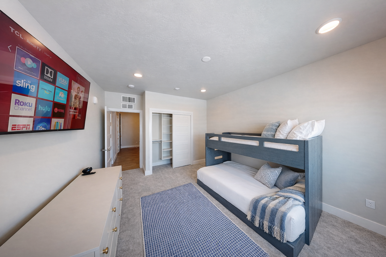 Perfect for kids or groups, this modern bunk room features sleek gray beds and a cozy blue gingham rug. Large windows offer bright, natural light and peaceful mountain views.