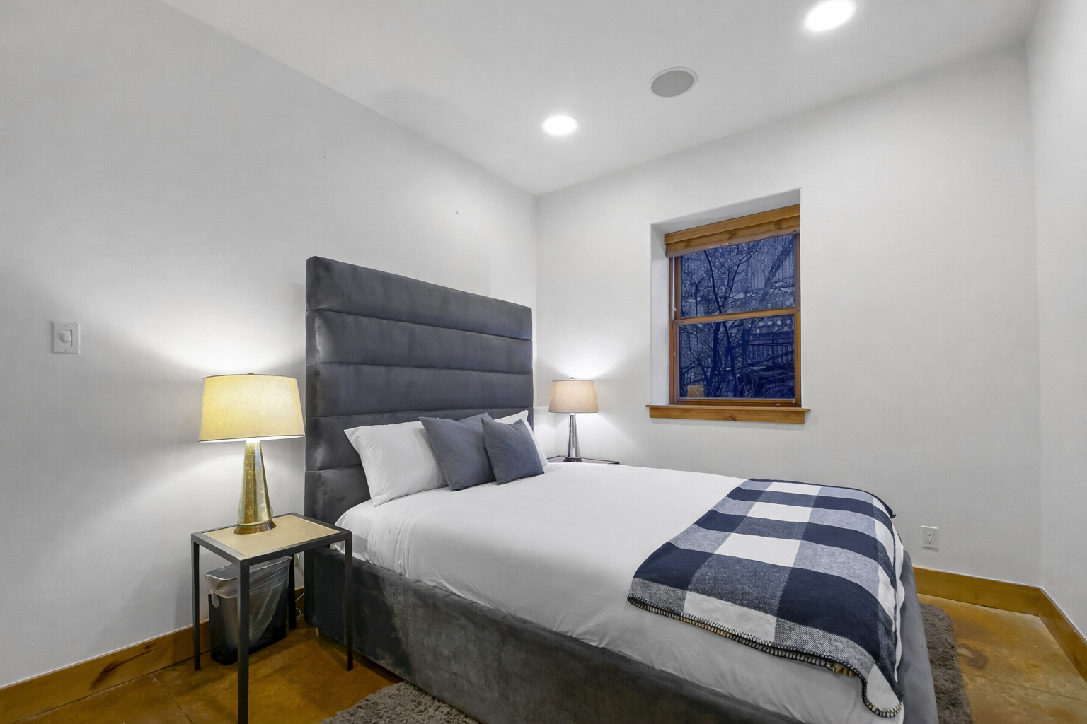 Retreat to this cozy bedroom featuring a plush bed with a stylish blue headboard and warm knotty pine doors. A tranquil space for a restful stay.