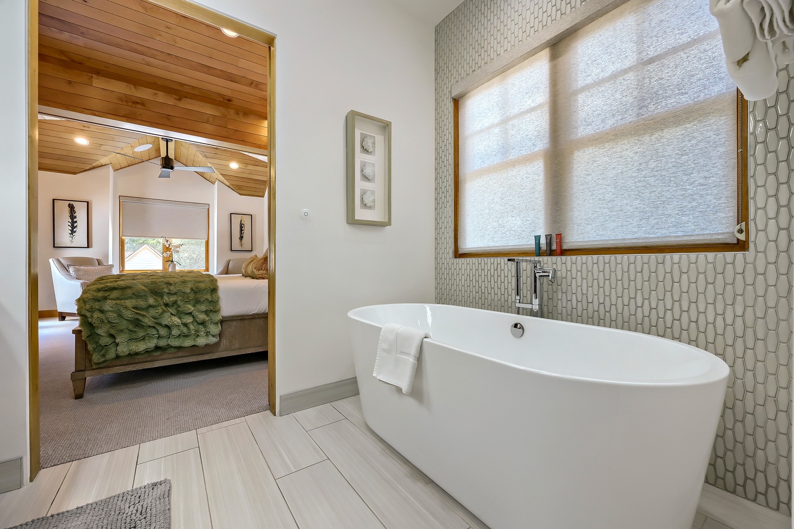 Sink into your own private spa moment in this elegant freestanding soaking tub, perfectly positioned with natural light and a view into the cozy bedroom beyond.